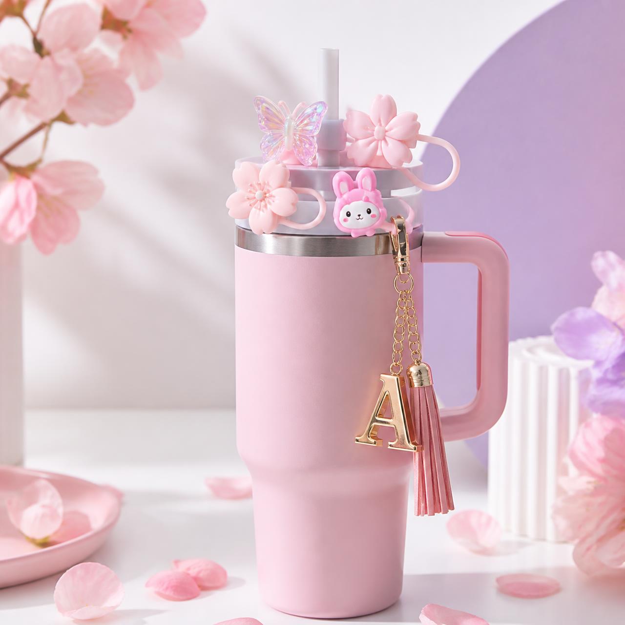 Pink tumbler decorated with butterfly, cherry blossom, bow and letter charm accessories